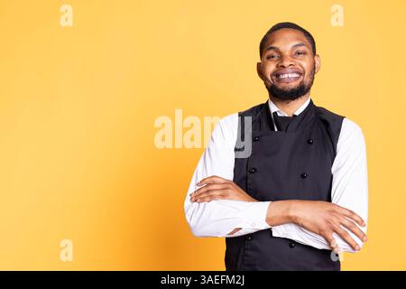 Porträt des Kellners im Restaurant in professioneller Uniform und Schürze, der sich bereit macht, den Gästen zu helfen und sie zu bedienen. Mitarbeiter, die in serviceorientierter Umgebung zur Kundenzufriedenheit arbeiten. Stockfoto