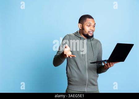 Positiver, fröhlicher afroamerikaner, der mit seinen Freunden auf Video diskutiert, mit seinen Freunden plaudert und tratscht. Junger Erwachsener war mit seinem Online-Telefonkonferenztreffen zufrieden. Stockfoto