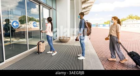 Flughafen Soziale Distanzierung. Passagiere mit Masken stehen an der Reihe zum Terminal-Eingang Stockfoto