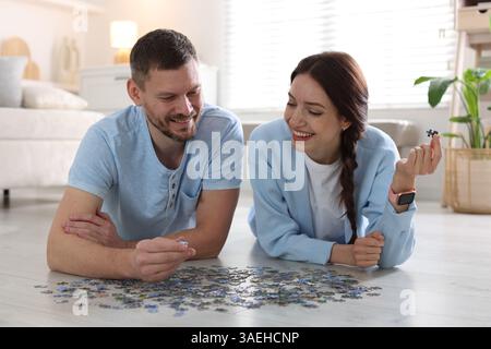 Glückliches Paar löst zusammen Puzzle auf dem Boden drinnen Stockfoto
