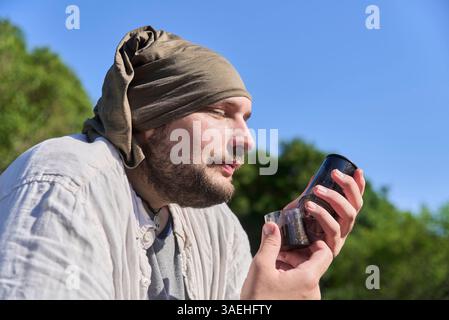 Konzept: Genießen Sie die kleinen Dinge des Alltags. Hispanischer Mann, der draußen sitzt und das Aroma des frisch gemahlenen Kaffees mit seinem Reisemahl genießt Stockfoto