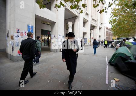 31. Oktober 2011 - London - Ein Mann in Bowler-Hut und -Anzug geht am 31. Oktober 2011 vor der St Pauls Cathedral in Central London über den Protest von Occupy London. Der Dekan der St. Paul's Cathedral in London wurde am Montag das zweite hochkarätige Geistliche Mitglied, das aufgrund der zunehmenden Kontroverse über antikapitalistische Proteste auf dem Kirchengelände zurücktrat. (Kreditbild: © Ki Price/ZUMAPRESS.com) Stockfoto