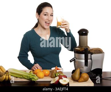 Schöne Frau trinkt und genießt einen frisch gepressten Bio-Fruchtsaft mit ihrem Entsafter in der Küche, isoliert, New York, USA, Nordamerika Stockfoto