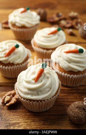 Leckere Karotten-Cupcakes und Walnüsse auf Holztisch, Nahaufnahme Stockfoto