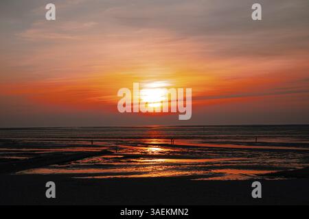 Leuchtender Sonnenuntergang über dem Wattenmeer mit intensiven Orange- und Rottönen, beruhigende Atmosphäre, Nordseestrand 27476 Cuxhaven/Sahlenburg-Deutschland Stockfoto