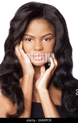 Schöne afroamerikanische junge Frau mit sauberer Haut und Händen im Gesicht und großen Perücke Haarverlängerungen, Make-up Kosmetik Haarpflegekonzept, auf weiß, ATL Stockfoto