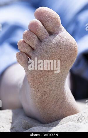 Ein sandiger Fuß einer liegenden Frau in Nahaufnahme am Strand, Groede, Zeeland, Niederlande Stockfoto