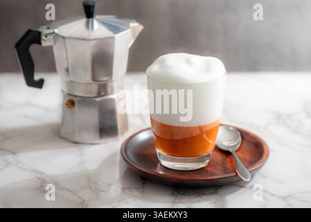 Heißer Thai Tee Latte mit Milchschaum im Glas. Stockfoto
