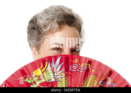Schöne ältere Frau mit grauem Haar und rotem chinesischen Drachenfan, isoliert, New York, USA, Nordamerika Stockfoto