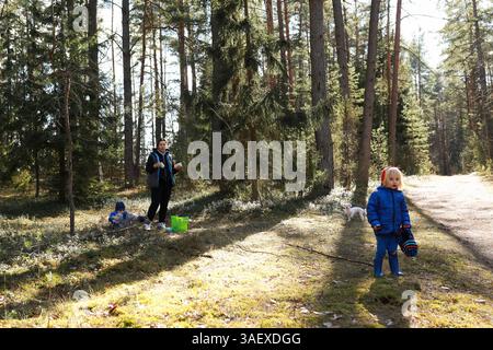 Die Familie genießt einen sonnigen Tag im Wald, während Kinder spielen und die Natur in der Nähe eines bewaldeten Weges erkunden Stockfoto