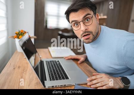 Porträt eines überraschten Mannes, der in die Kamera schaut, während er am Schreibtisch sitzt Stockfoto