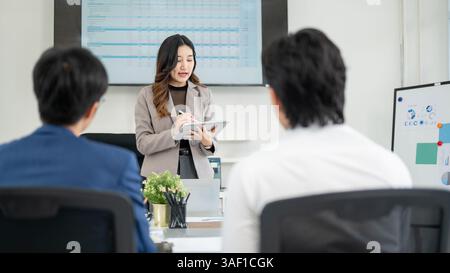 Büroangestellte schreibt auf einem digitalen Tablet, während sie mit ihren männlichen Kollegen spricht. Geschäftsmann und Geschäftsfrau haben ein Meeting im Büro. Stockfoto