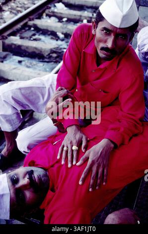 April 2003; Bombai, INDIEN; „Coolies“, oder die Träger entspannen sich, während sie auf den nächsten Zug warten, der am Bahnhof Bombay Central ankommt. Stockfoto