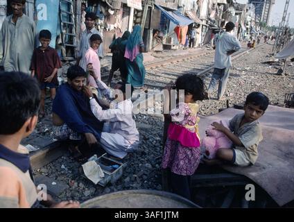 20. April 2003; Bombai, INDIEN; Ein stillgelegtes Eisenbahngleis in einem Slum von Bombay bietet einen bequemen Ort für einen Haarschnitt in Bombay, Indien. Stockfoto