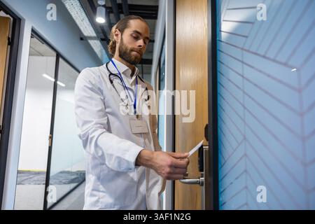 Bärtiger Mann Doktor, der ihre Zugangskarte auf den Scanner an der Krankenhaustür drückt, um sie zu öffnen Stockfoto
