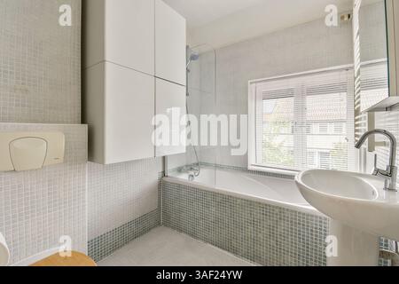 Ein stilvolles, modernes Badezimmer mit einer eleganten Badewanne, modernen Armaturen und Fliesen in neutralen Farben sorgen für eine ruhige Atmosphäre. Stockfoto