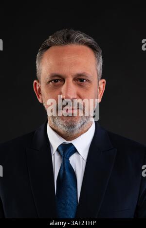Professionelles Studio-Porträt eines ernsten, Reifen Mannes in dunklem Anzug und Krawatte, der vor schwarzem Hintergrund steht. Unternehmen und Unternehmensführung Co Stockfoto