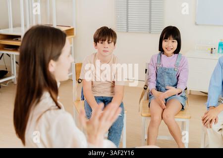 Glückliche asiatische Kinder in einem Klassenzimmer, die aktiv an einer Lektion teilnehmen und das Wesen des Gruppenlernens, der Kommunikation und des Engagements in einem festhalten Stockfoto
