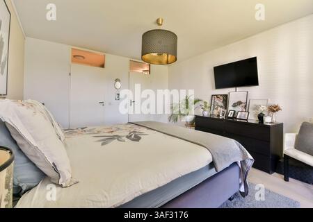 Gemütliches Wohnzimmer mit modernen Möbeln, einer stilvollen Leuchte und einem an der Wand montierten Fernseher schaffen eine komfortable und schicke Umgebung. Stockfoto