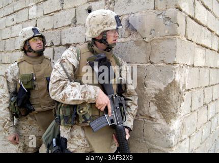 9. März 2005; Falludscha, Irak; während einer Patrouille durch die Stadt Falludscha, Irak, schaut Petty Officer 2. Klasse AARON G. NEELY, 21-jähriger Spezialist für religiöse Programme des 3. Bataillons, 4. Marines, Regimentskampfteam-1, um eine Ecke, um MARINELEUTNANT MATTHEW S. WEEMS, 33 Jahre alter Bataillonsseur, den Weg frei zu machen. Weems und Neely nehmen an vielen verschiedenen Aspekten der Operationen des Bataillons Teil, um eine Präsenz unter den Marines zu erhalten. Stockfoto