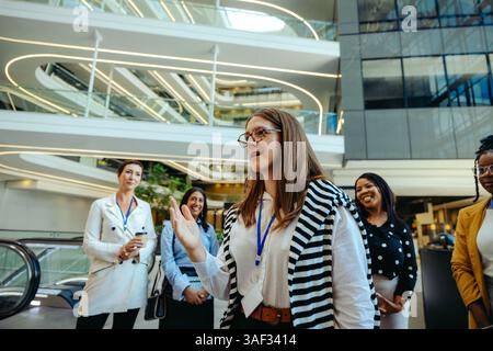 Eine Gruppe selbstbewusster weiblicher Fachkräfte, die an einer Networking-Veranstaltung in einer modernen Unternehmensumgebung teilnehmen. Lächelnd und unterredend, das hier Stockfoto