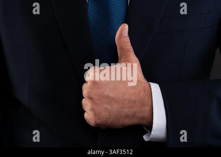 Nahaufnahme einer Hand, die einen dunklen Anzug und ein weißes Hemd trägt, um Anerkennung und Erfolg im Geschäft zu symbolisieren. Stockfoto