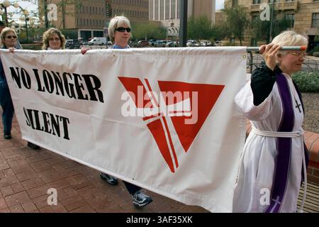 Januar 2005; Phoenix, AZ, USA; Rev. STEPHANIE BIKEL (R) von Desert Surprise United Church of Christ in Surprise, AZ, führt einen stillen marsch von Geistlichen durch die Innenstadt von Phoenix in die Hauptstadt des Bundesstaates Arizona, um gegen die Pläne der Legistlatures zu protestieren, eine Verfassungsänderung des Staates zu debattieren, die schwule Ehe verbieten würde. Der Klerus, Mitglieder von nicht mehr Silent, einer Organisation christlicher Geistlicher, die die Rechte schwuler Ehe unterstützt. Etwa 200 Menschen nahmen an dem marsch Teil. Stockfoto