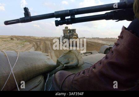 16. Januar 2005; Zeitoun, GAZASTREIFEN; ein israelischer Armeesoldat wacht über einen gepanzerten Bulldozer, der während einer Militäroperation gegen palästinensische Militanten am 16. Januar 2005 in Zeitoun nahe Gaza-Stadt im Gazastreifen einen Weg für seinen gepanzerten Personentransporter freigibt. Der israelische Premierminister Ariel Sharon beschuldigte die Palästinensische Autonomiebehörde unter ihrem neu gewählten Präsidenten Mahmud Abbas, keine Anstrengungen zur Bekämpfung militanter palästinensischer Aktivitäten unternommen zu haben, und sagte, die israelischen Verteidigungskräfte hätten freie Hand, um den aus dem Gazastreifen ausgehenden Terrorismus zu bekämpfen. Stockfoto