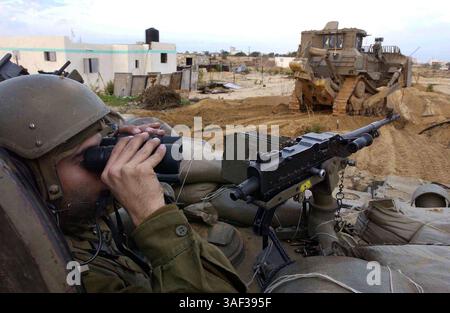 16. Januar 2005; Zeitoun, GAZASTREIFEN; ein israelischer Armeesoldat wacht über einen gepanzerten Bulldozer, der während einer Militäroperation gegen palästinensische Militanten am 16. Januar 2005 in Zeitoun nahe Gaza-Stadt im Gazastreifen einen Weg für seinen gepanzerten Personentransporter freigibt. Der israelische Premierminister Ariel Sharon beschuldigte die Palästinensische Autonomiebehörde unter ihrem neu gewählten Präsidenten Mahmud Abbas, keine Anstrengungen zur Bekämpfung militanter palästinensischer Aktivitäten unternommen zu haben, und sagte, die israelischen Verteidigungskräfte hätten freie Hand, um den aus dem Gazastreifen ausgehenden Terrorismus zu bekämpfen. Stockfoto