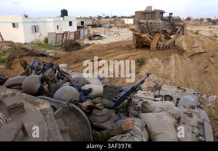 16. Januar 2005; Zeitoun, GAZASTREIFEN; ein gepanzerter Bulldozer der israelischen Armee bereitet während einer Militäroperation gegen palästinensische Militanten am 16. Januar 2005 in Zeitoun nahe Gaza-Stadt im Gazastreifen einen Weg für einen gepanzerten Personentransporter frei. Der israelische Premierminister Ariel Sharon beschuldigte die Palästinensische Autonomiebehörde unter ihrem neu gewählten Präsidenten Mahmud Abbas, keine Anstrengungen zur Bekämpfung militanter palästinensischer Aktivitäten unternommen zu haben, und sagte, die israelischen Verteidigungskräfte hätten freie Hand, um den aus dem Gazastreifen ausgehenden Terrorismus zu bekämpfen. Stockfoto