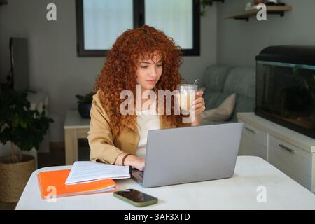 Zielgerichtete junge Frau, die von zu Hause aus mit einem Laptop arbeitet Stockfoto