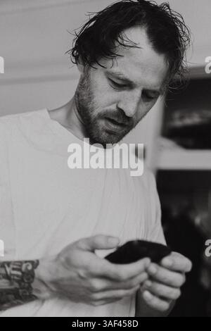 Junger Mann, Blick auf Handy Stockfoto