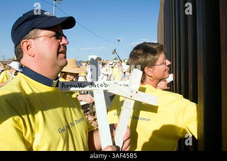 April 2005; Naco, AZ, USA; die Menschen passieren die Kreuze, die sie durch die Grenzmauer zwischen den USA und Mexiko trugen, zu den Menschen auf der mexikanischen Seite der Grenze während einer interreligiösen Prozession und eines Gebetsgottesdienstes in Naco, AZ. Die Teilnehmer kamen aus Kirchen in Bisbee, Naco, Tucson und Douglas, Arizona und Naco, Mexiko, zusammen. um gegen die Aktionen der Freiwilligen des Minuteman-Projekts zu protestieren. Etwa 250 Menschen aus Arizona und Mexiko nahmen an der Veranstaltung Teil. Das Minuteman Project ist ein freiwilliges Projekt, um illegale Einwanderer davon abzuhalten, ohne Dokumente in die USA einzureisen. Der Minuteman Freiwillige c Stockfoto