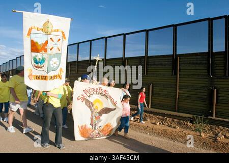 April 2005; Naco, AZ, USA; die Teilnehmer spazieren entlang der Grenzmauer zwischen den USA und Mexiko während einer interreligiösen Prozession und einem Gebetsgottesdienst in Naco, AZ. Die Teilnehmer kamen aus Kirchen in Bisbee, Naco, Tucson und Douglas, Arizona und Naco, Mexiko, zusammen. um gegen die Aktionen der Freiwilligen des Minuteman-Projekts zu protestieren. Etwa 250 Menschen aus Arizona und Mexiko nahmen an der Veranstaltung Teil. Das Minuteman Project ist ein freiwilliges Projekt, um illegale Einwanderer davon abzuhalten, ohne Dokumente in die USA einzureisen. Die Minuteman-Freiwilligen rufen die Grenzpolizei an, wenn sie Einwanderer ohne Papiere sehen Stockfoto