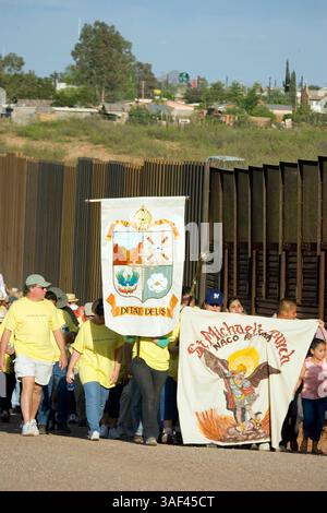 April 2005; Naco, AZ, USA; während einer interreligiösen Prozession und eines Gebetsgottesdienstes in Naco, AZ, laufen die Teilnehmer entlang der Grenzmauer zwischen den USA und Mexiko, mit Mexiko im Hintergrund. Die Teilnehmer kamen aus Kirchen in Bisbee, Naco, Tucson und Douglas, Arizona und Naco, Mexiko, zusammen. um gegen die Aktionen der Freiwilligen des Minuteman-Projekts zu protestieren. Etwa 250 Menschen aus Arizona und Mexiko nahmen an der Veranstaltung Teil. Das Minuteman Project ist ein freiwilliges Projekt, um illegale Einwanderer davon abzuhalten, ohne Dokumente in die USA einzureisen. Die Minuteman-Freiwilligen rufen die Grenzpolizei an, wenn sie sehen Stockfoto