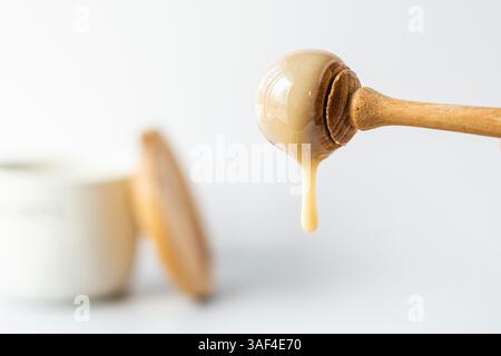 Honig tropft aus einem Honiglöffel Stockfoto