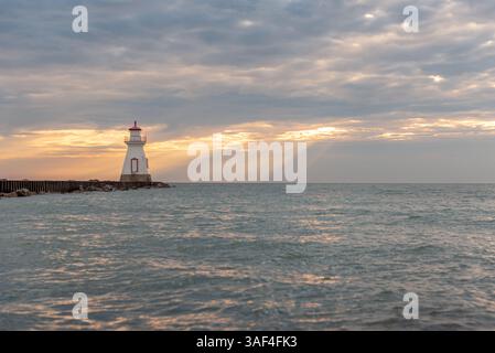 Der wunderschöne Leuchtturm befindet sich am Ende des Piers mit einem stimmungsvollen Sonnenuntergang Stockfoto