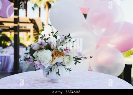 Mittelstück mit pastellfarbenem Blumenmuster und rosa und weißen Ballons dahinter. Stockfoto