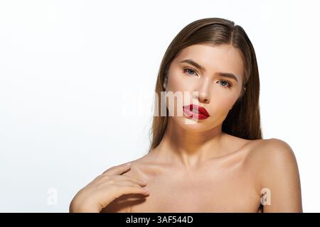 Eine junge Frau posiert elegant und zeigt ihren stilvollen Look und ihre auffälligen roten Lippen. Stockfoto