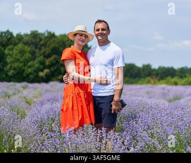 Glückliches Paar, das an einem sonnigen Sommertag im blühenden Lavendelfeld steht Stockfoto