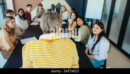 Eine vielfältige Gruppe junger Schüler hört einem Lehrer während einer Unterrichtssitzung zu und fördert das Engagement und Lernen in einer Bildungsumgebung. Stockfoto