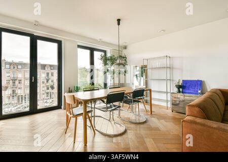 Stilvolle Innenausstattung mit Holzfußboden, modernen Möbeln und großen Fenstern, die viel natürliches Licht liefern, ideal für ein modernes Wohnen. Stockfoto