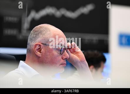 07. April 2025, Hessen, Frankfurt/Main: Während ein Händler auf der Börse der Frankfurter Wertpapierbörse seine Monitore beobachtet, ist im Hintergrund die Anzeigetafel mit der Dax-Kurve zu sehen. Zu Beginn der neuen Handelswoche sank der deutsche Aktienindex (Dax) um rund zehn Prozent. Foto: Arne Dedert/dpa Stockfoto