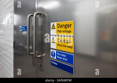 Metalltüren mit mehreren Sicherheitswarnschildern im öffentlichen Infrastrukturbereich Stockfoto