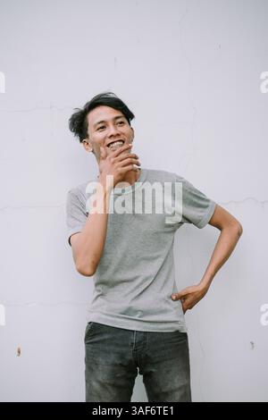 Glücklicher junger Mann in lässigen Kleidern, der aufblickt und lächelt. Porträt eines lächelnden Mannes, der an etwas Positives denkt. Stockfoto