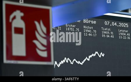 07. April 2025, Hessen, Frankfurt/Main: An einer Passage der Frankfurter Wertpapierbörse ist ein Feuerlöschschild zu sehen, während die Anzeigetafel mit der Dax-Kurve die Preise anzeigt. Zu Beginn der neuen Handelswoche sank der deutsche Aktienindex (Dax) um rund zehn Prozent. Foto: Arne Dedert/dpa Stockfoto