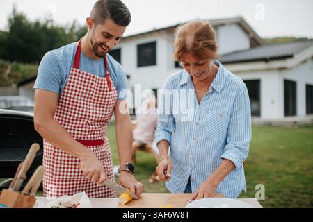 Erwachsener Sohn und Mutter bereiten Essen für ein Familiengrill vor. Stockfoto