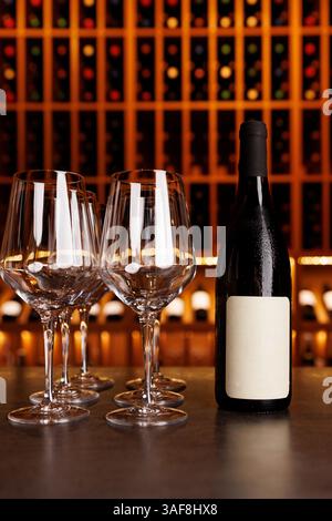 Eine Flasche Wein steht auf einem Tisch neben vier Weingläsern. Die Szene spielt in einer Bar oder einem Restaurant Stockfoto