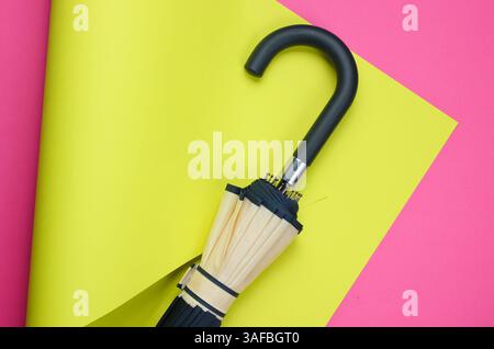 Regenschirmhaken auf farbigem gefaltetem Papierhintergrund. Minimalistisches Fashion Stillleben. Flache Lagen. Draufsicht Stockfoto
