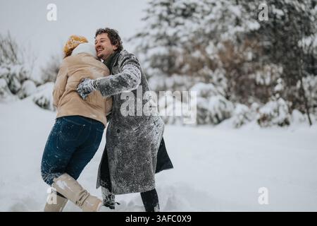 Verspieltes Paar genießt Winterspaß im Freien in einer verschneiten Umgebung Stockfoto
